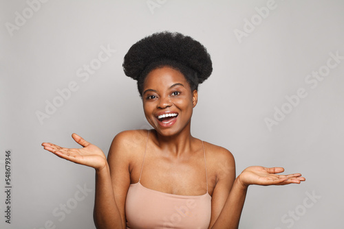 Happy joyful pretty woman showing her empty palm hands on white studio wall background