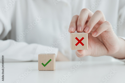 Human pick wrong or red cross icon on wood cube from green check mark for true or false mindset or elections vote, survey and assessment to change leader and transform quiz answer and poll concept. 