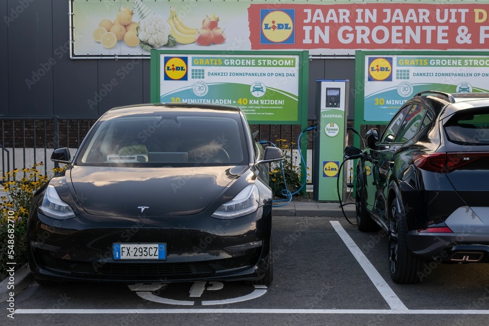 A static of a solid black Model 3 motor charging at the supermarket Stock Photo | Adobe Stock