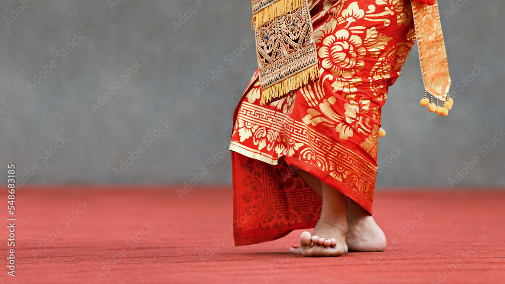Asian travel background. Beautiful Balinese dancer woman in traditional Sarong costume dancing Legong dance. Legs movements. Arts, culture of Indonesian people, Bali island festivals.