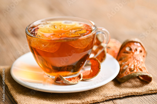 Bael tea on glass with dried bael slices on wooden background, Bael juice - Dry bael fruit tea for health - Aegle marmelos