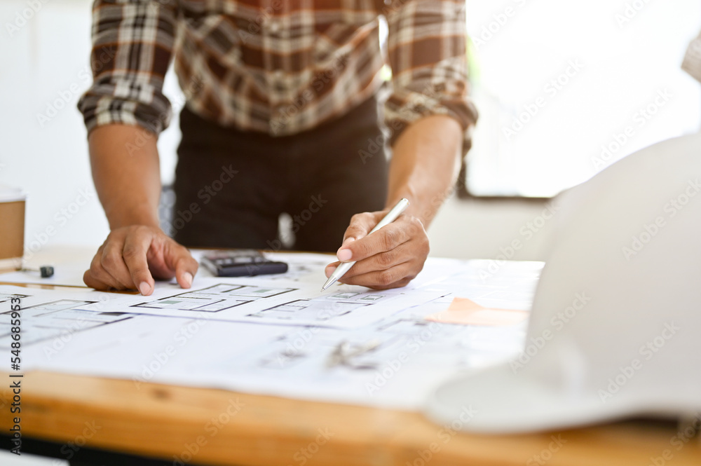 Asian male engineer or architect checking building scale, working on his blueprint in the office. Asian male engineer or architect checking building scale, working on his blueprint in the office.