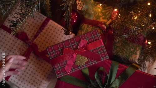Close-up view of hands putting Christmas gift under the xmas tree