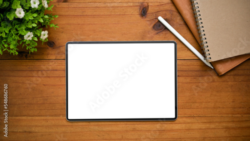 Digital tablet mockup is on a wooden tabletop background with decor. workspace top view