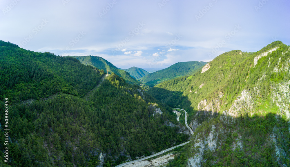 Winding track is like slopes of Rhodope Mountains with forests. Panorama, top view