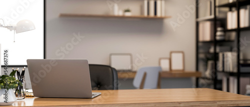 Minimalist bright desk in co-working office room with laptop and copy space on wooden table photo