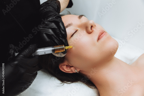 Print op canvas A cosmetologist performs plasmolifting on the face of a beautiful woman in a beauty salon