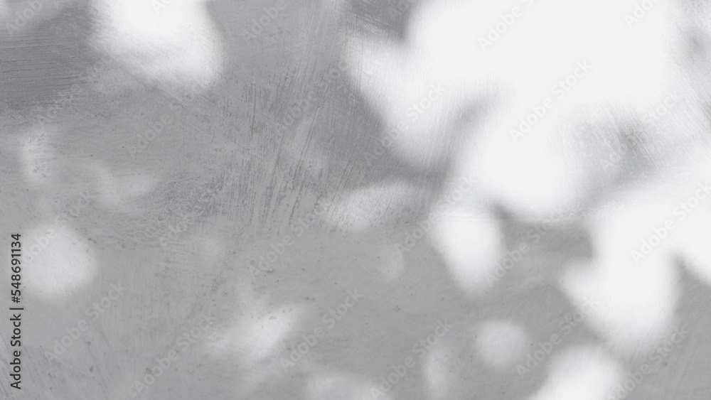 Abstract background with light spots from the shadow and reflection of tree leaves on a gray stone wall. Dimanic screensaver in natural style.