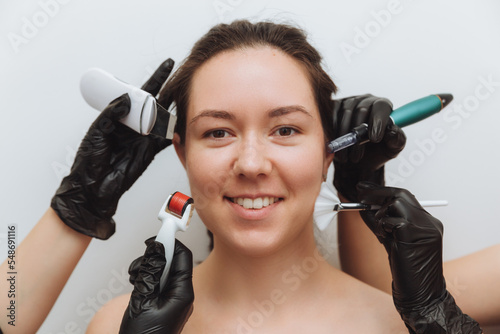 a woman with the hands of several therapists with cosmetology devices near her face, a woman needs skin care, skin care concept photo. photo