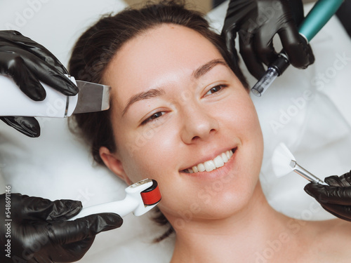 a woman with the hands of several therapists with cosmetology devices near her face, a woman needs skin care, skin care concept photo. photo