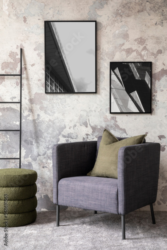 Loft and indiustral living room interior with mock up poster frame, stylish gray armchair, bottle green pillows, modern pouf, simple ladder and personal accessories. Home decor. Template. photo