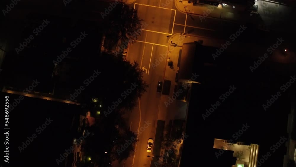 Aerial drone shot of empty street during the night. Low flying aerial tilting dolly shot of empty multi lane road in modern city center with skyscrapers at night
