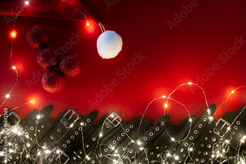 New year banner with penis from christmas balls and black leather bracers and metal rivets for shackling hands or legs and sexual games. BDSM entertainment. Background for adult toys or sex shop