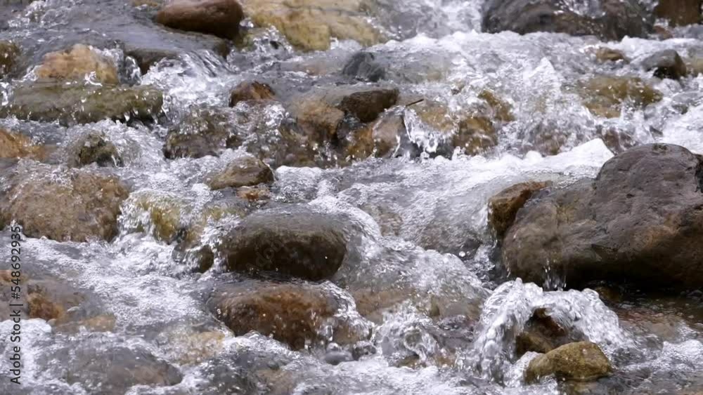 Clear stream running through stone boulders Abundant river flowing in slow motion. Wild mountain river water splashing in summer near the river bank environment. Clear stream running through stone boulders Abundant river flowing in slow motion. Wild mountain river water splashing in summer near the river bank environment.