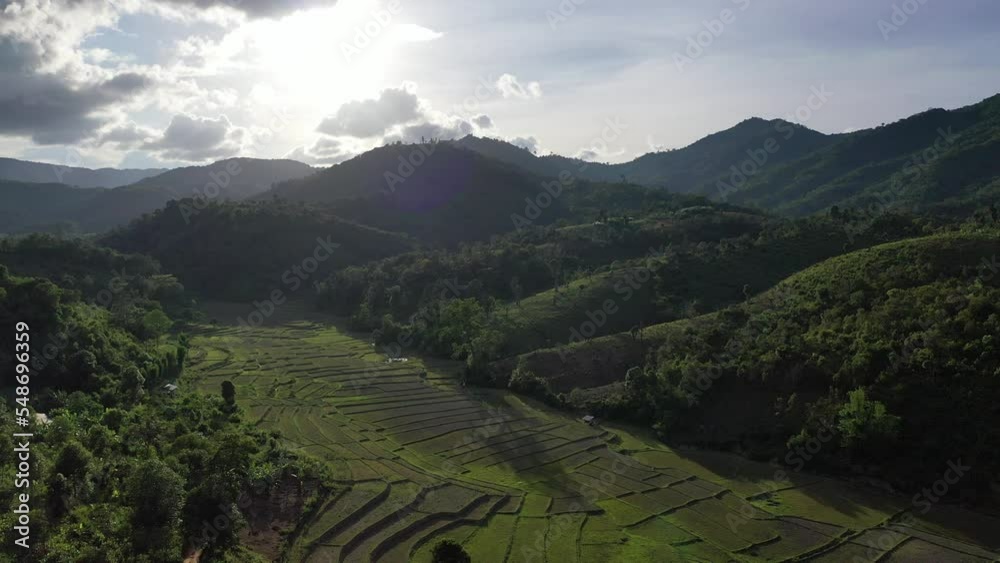 Aerial view of terraced agriculture field among greenery mountains with the blue cloudy and sunlight in the northern of Thailand, Omkoi district, Chiang Mai.