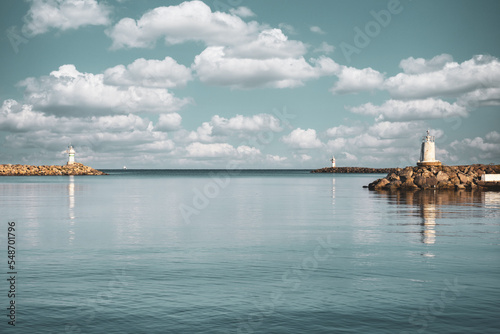 Two lighthouses facing each other in the port with clear sky and clouds. Clouds over the pier and lighthouses photo