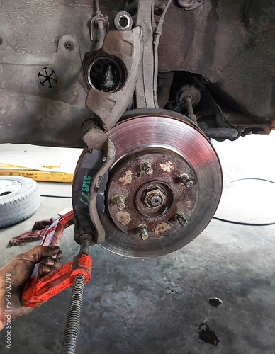 Car maintenance in a garage. The disc brake of a vehicle. Mechanic engineer is working on the brake.