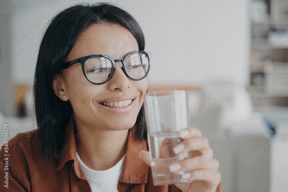 Happy female in glasses holding glass of pure mineral water. Healthy lifestyle habit, wellness, diet Happy female in glasses holding glass of pure mineral water. Healthy lifestyle habit, wellness, diet