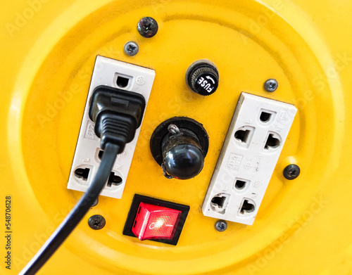 Yellow extension cord with red switch. Black cord connected to the plug with switch on.