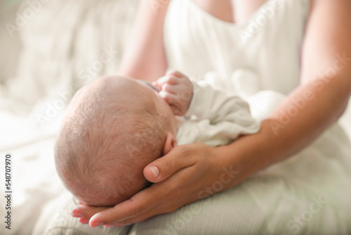 Mother holding newborn baby indoors, focus on head