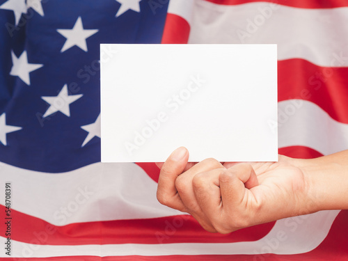 Hand holding a blank white paper against the American flag background