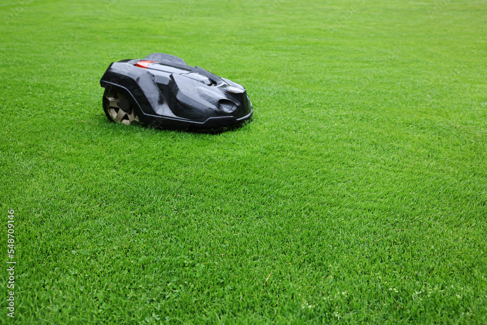 Modern lawn mower on green grass outdoors. Space for text Modern lawn mower on green grass outdoors. Space for text