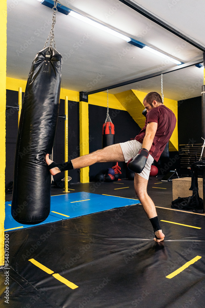 Young kickboxer kicking the punching bag with the sole of his foot