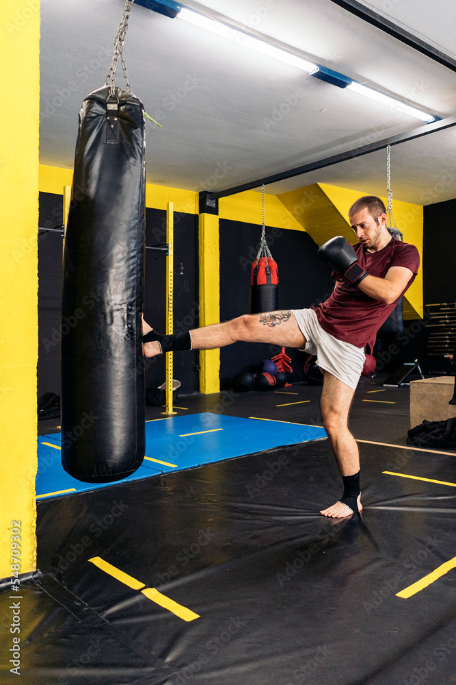 Young kickboxer kicking the punching bag with the sole of his foot