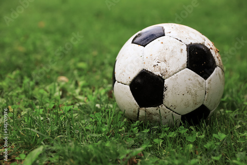 Dirty soccer ball on green grass outdoors, space for text © New Africa