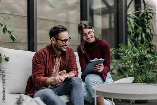 Foto Business people sitting next to each other, using a tablet, working
