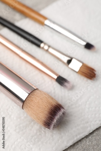 Clean makeup brushes with napkin on table, closeup
