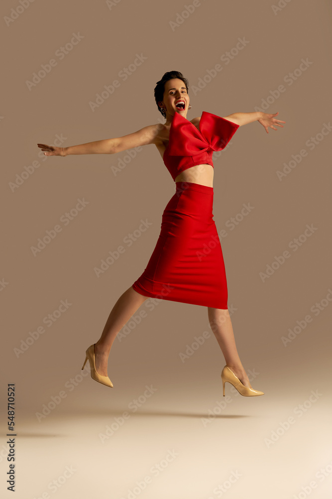 Girl in a red top with a bow in the style of a New Year's gift. Studio photo of a fashion girl with a short haircut