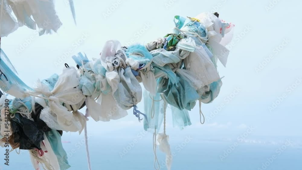 Waste during COVID-19. coronavirus disposable face masks tied on a tree ...