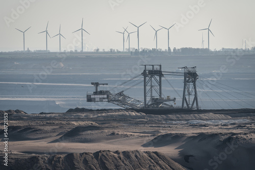 View of surface mine in Germany, heavy machinery in lignite mine and wind turbines in the background