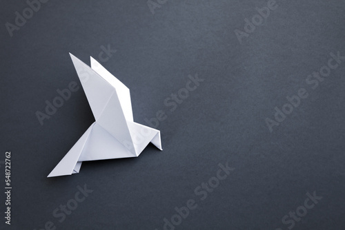 White paper dove origami isolated on a grey background photo