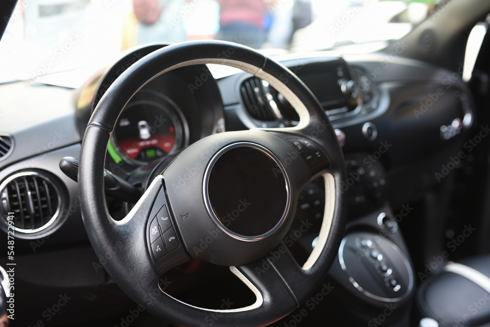 Steering wheel of an electric modern car. Car interior. Driver's seat with steering wheel and electronic display, navigation, climate control and other options. Perforated leather and seat ventilation