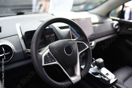 Steering wheel of an electric modern car. Car interior. Driver's seat with steering wheel and electronic display, navigation, climate control and other options. Perforated leather and seat ventilation © MaxSafaniuk