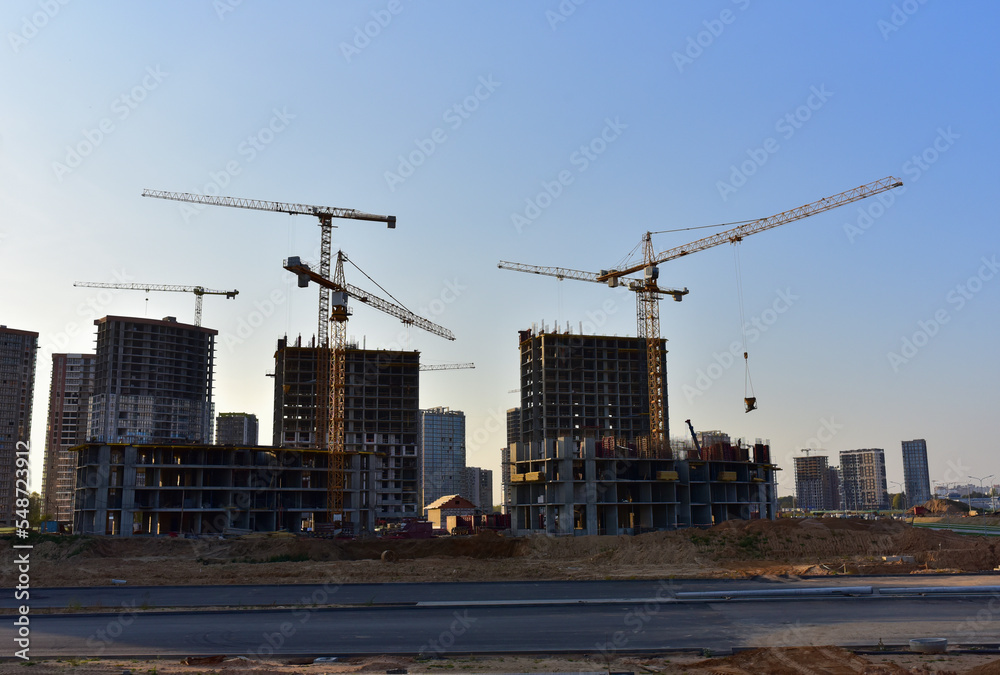 Сonstruction site with tower cranes on building construction. Builder on formworks. Cranes on pouring concrete in formwork. Tower cranes on construction in built environment. Buildings renovation.. Сonstruction site with tower cranes on building construction. Builder on formworks. Cranes on pouring concrete in formwork. Tower cranes on construction in built environment. Buildings renovation..