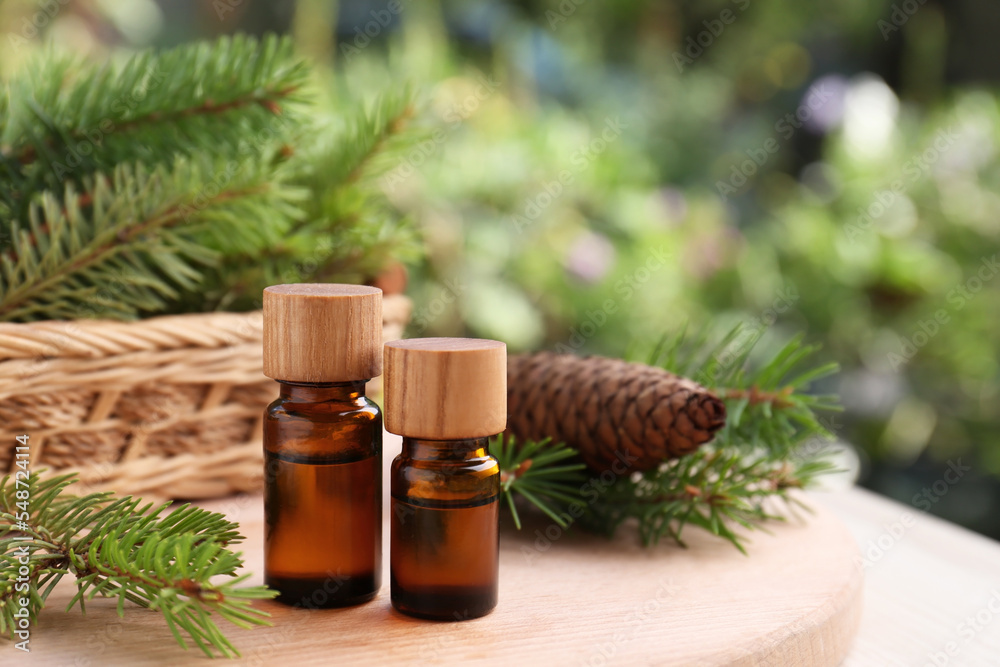 Bottles of pine essential oil, cone and branches on wooden table, closeup. Space for text Bottles of pine essential oil, cone and branches on wooden table, closeup. Space for text
