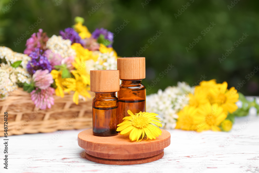 Bottles of essential oils and beautiful flowers on white wooden table Bottles of essential oils and beautiful flowers on white wooden table