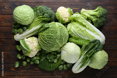 Many different types of fresh cabbage on wooden table, flat lay photo