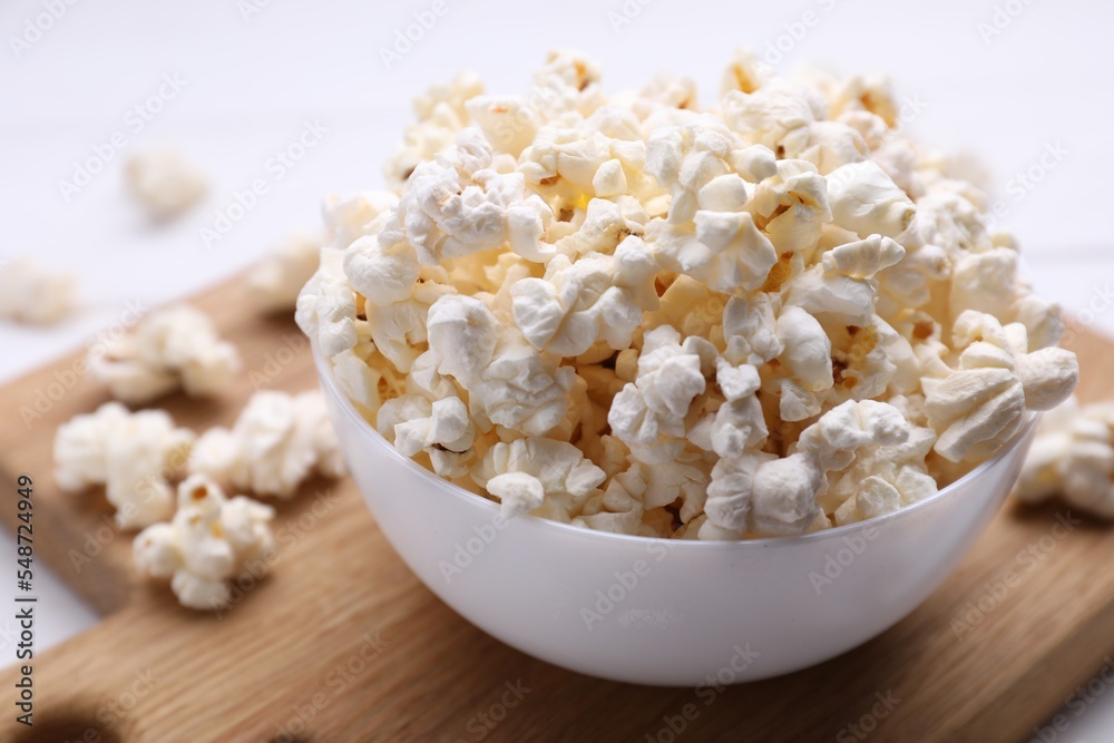 Tasty popcorn in bowl on wooden board, closeup Tasty popcorn in bowl on wooden board, closeup