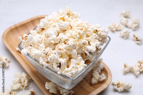 Bowl of tasty popcorn on white table, closeup