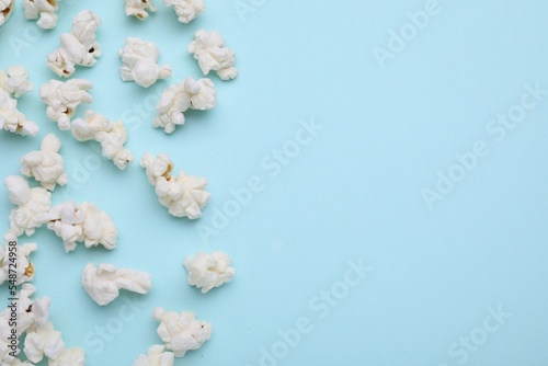 Fototapeta Naklejka Na Ścianę i Meble -  Tasty popcorn on light blue background, flat lay. Space for text