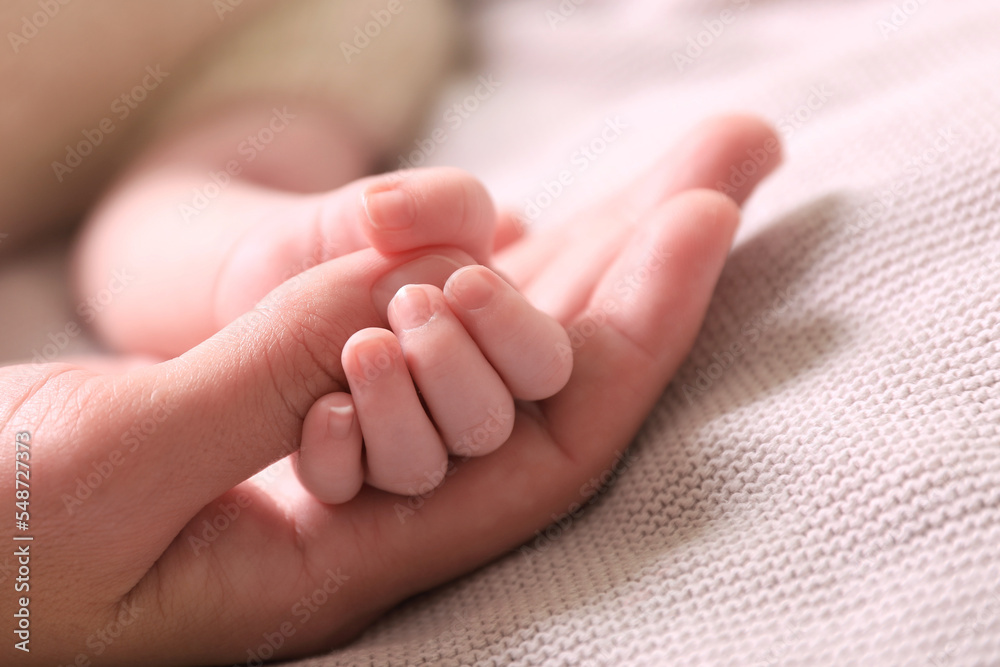 Mother and her newborn baby on light grey knitted plaid, closeup Mother and her newborn baby on light grey knitted plaid, closeup