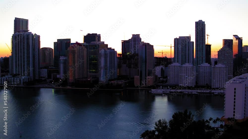 Aerial Shot Of Airplane Flying By Modern Buildings In City, Drone Flying Forward Over Ocean During Sunset - Miami, Florida Aerial Shot Of Airplane Flying By Modern Buildings In City, Drone Flying Forward Over Ocean During Sunset - Miami, Florida