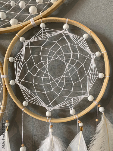 Close-up white feathers dreamcatcher craft on gray background