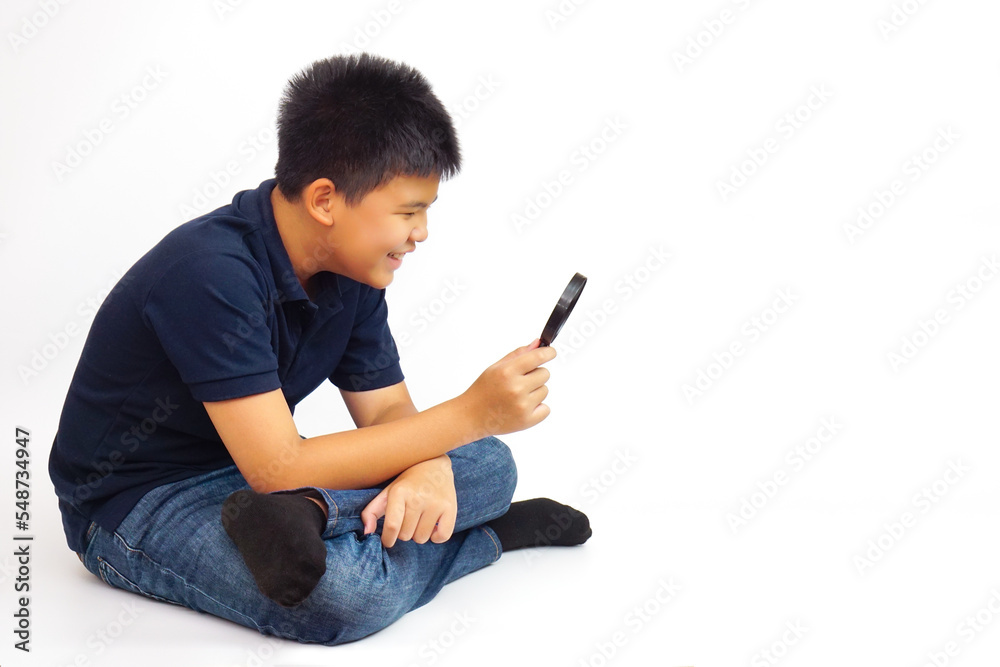 Boy holding a magnifying glass on white background. Knowledge, research and explore concept.