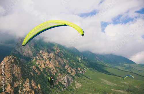 Paragliders are flying over mountains in cloudy summer day over the Chegem gorge, Caucasus