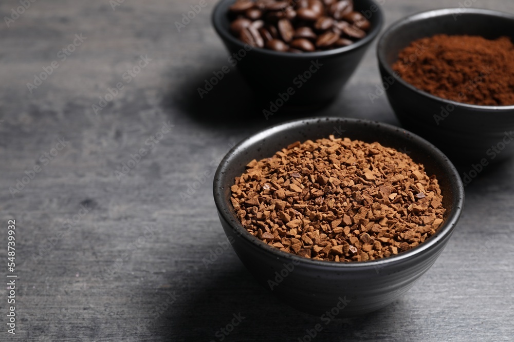 Bowls of beans, instant and ground coffee on grey table, closeup. Space for text Bowls of beans, instant and ground coffee on grey table, closeup. Space for text